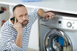 © auremar - man fed up during call to washing machine helpline