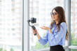 © Maksymiv Iurii - Young business woman recording video blog on smartphone in company office