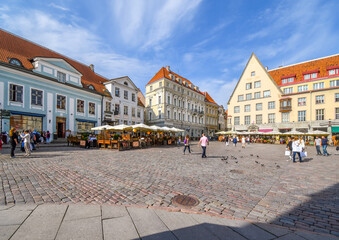 Wall Mural - Tourists enjoy a summer afternoon eating at cafes and shopping in the Old Town Hall Square in the touristic center of Medieval Tallinn Estonia.