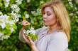 © Elena  - Portrait of a fat plump young woman with red hair and a blooming apple tree on a white floral background in a park on a spring day. Happy plus-size girl.