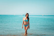 © _KUBE_ - Summer. A young pretty woman poses standing at the ocean. The concept of summer holidays. Copy space