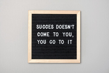 Wall Mural - Success doesn't come to you, you go to it. Motivational quote on black letter board on gray background. Concept inspirational quote of the day. Greeting card, postcard