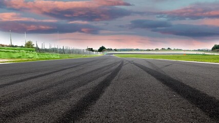 Wall Mural - Motorsport background skid marks on asphalt track, suddenly screeching halt and stop concept, empty competition circuit no people, scenic landscape sunset sky