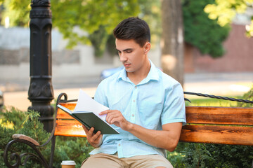 Wall Mural - Young man reading book in park