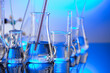 © zolnierek - Laboratory concept background. Glass tubes and beakers on blue background.