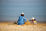 Fototapeta Kosmos - 初夏の海で砂遊びしている親子の姿