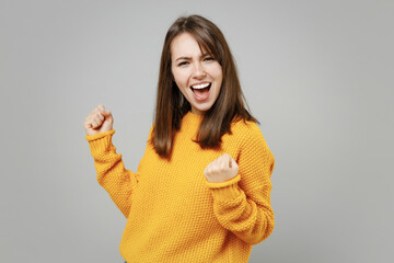 young excited happy overjoyed attractive beautiful woman in casual knitted yellow sweater do winner 