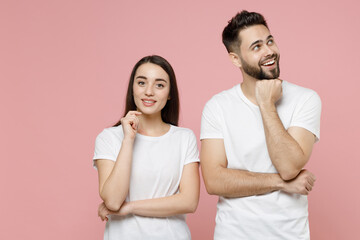 Poster - Young pensive couple two friends bearded man brunette woman in white basic blank print design t-shirts thinking dream put hand prop up on chin isolated on pastel pink color background studio portrait.