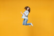 Full length of young overjoyed excited fun student happy woman 20s in denim shirt white t-shirt do winner gesture clench fist celebrating jump high isolated on yellow color background studio portrait