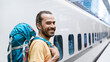 © Syda Productions - travel, tourism and people concept - smiling middle eastern man with backpack traveling over train on railway station on background