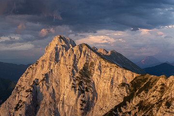 Poster - Mesmerizing view of high rocky mountains at sunset under the cloudy sky in Slovenia