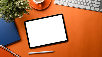 Fototapete - Top view of creative designer workspace with digital tablet, wireless keyboard, notebook, stylus pen and coffee cup on orange background.