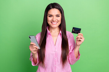 Poster - Portrait of attractive trendy cheerful girl holding in hands device card web order shopping isolated over green pastel color background