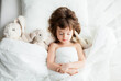 © Anna Lurye - Adorable little girl sleeping in white bed with rabbit toys