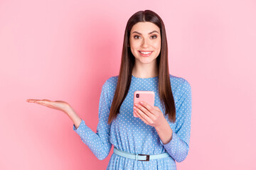 Poster - Photo of young charming good mood lovely girl demonstrate product use smartphone isolated on pink color background