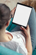 © perfectlab - Young woman using digital tablet while sitting in a comfortable amchair at home, mock up