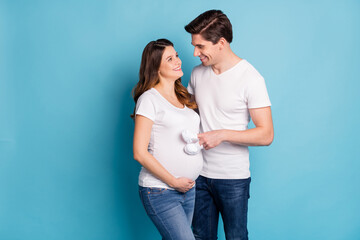 Poster - Profile portrait of two persons look each other eyes baby booties on fingers stomach isolated on blue color background