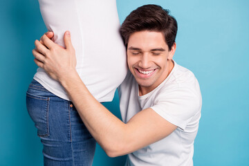 Poster - Cropped photo of impressed man hug listen baby in stomach closed eyes wear white t-shirts isolated on teal color background