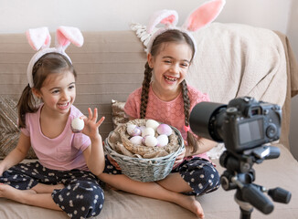 two cute little girls posing in front of the camera with a basket of easter eggs.
