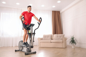 Canvas Print - Man using modern elliptical machine at home