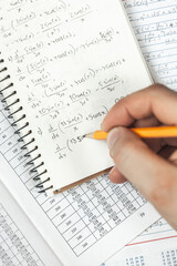 Math formulas are written in pencil in a notebook holding man in hands, math problems