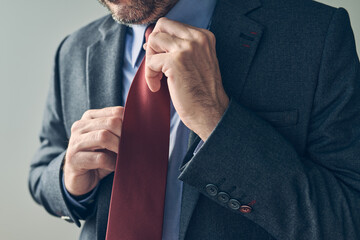 Businessman in elegant suit tying a red necktie