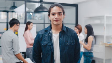 Portrait of successful handsome executive businessman smart casual wear looking at camera and smiling, happy in modern office workplace. Young Asia guy standing relax in contemporary meeting room.