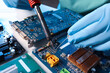 Technician repairing electronic circuit board with soldering iron at table, closeup