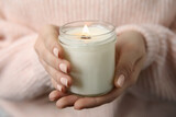 Woman holding burning candle with wooden wick, closeup