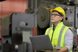 © Akarawut - Asian engineering manager in safety hard hat and reflective cloth is inspecting inside the factory using digital laptop with copy space
