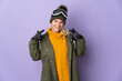 © luismolinero - Skier Russian girl with snowboarding glasses isolated on purple background giving a thumbs up gesture