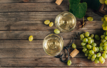 Two glasses of white wine and grape on vintage wooden table