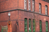 Green patina copper fence in front of old green orange red brick wall of an old building corner and huge windows. Architecture detail of Klaipeda historical center