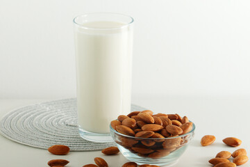 A glass with almond milk and the bowl with almonds