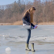 the girl looks at a wet sock on the lake ice 