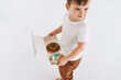 Funny cute toddler boy with box of donuts on rge white background, studio shot