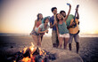 © oneinchpunch - Group of friends having fun on the beach making a bonefire. People spending time together in california, los angeles