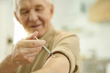 Wall Mural - Calm aged man sticking syringe into his arm