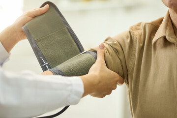 Wall Mural - Doctor preparing patient to have blood pressure measured with manometer