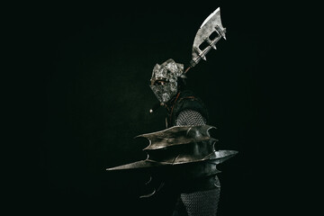 Wall Mural - Medieval fighter in armor, in profile, carrying a shield and an ax on his shoulder, in attack position