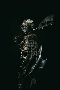 Medieval fighter in armor, in profile, carrying a shield and an ax on his shoulder