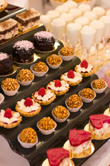 Single serving desserts on a modern stand of a buffet table, wedding candy bar