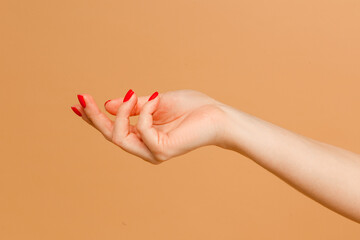 Wall Mural - Close up photo of woman enjoying her beauty. Attractive hands with manicure of young woman isolated on beige background.