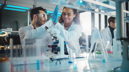 Wall Mural - modern medical research laboratory: portrait of latin, black young scientists using microscope and g
