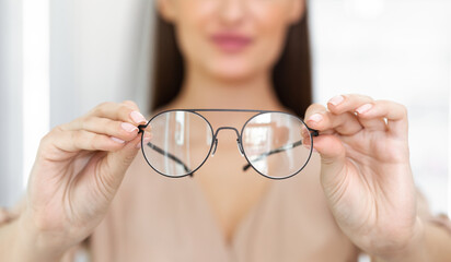 Closeup portrait of young woman showing spectacles to camera