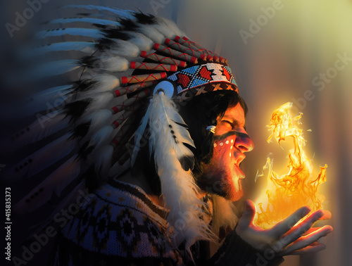Plakat Portrait of a young handsome guy in a hat with a feather of the chief of the Indians. Fire and man - portrait