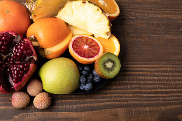  Selection of sliced fresh fruits with kiwis and blood orange on a plate on wooden background with free text space