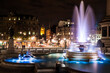 Illuminated fountain in Trafalgar Square taken at night time.