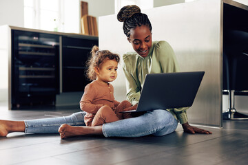 Wall Mural - Smiling mother and little girl watching something on a laptop