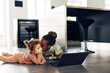 © Flamingo Images - Mom kissing her little girl while watching something on a laptop